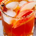 Apple Cider Margarita with Apples and a Cinnamon Stick Served in a Glass Rimmed with Sugar