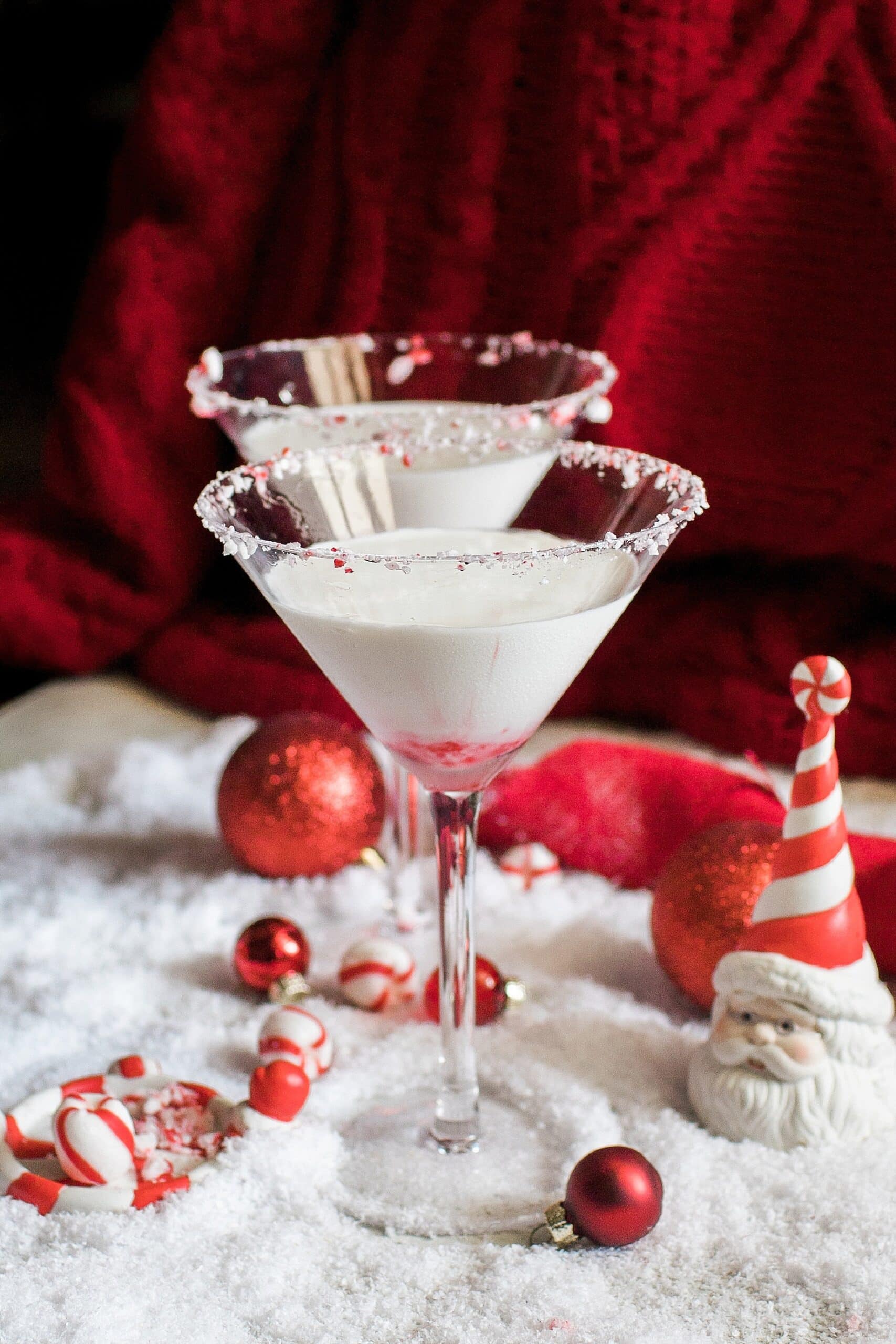 peppermintini-scaled-1 Two festive martinis with candy canes and red and white decorations.