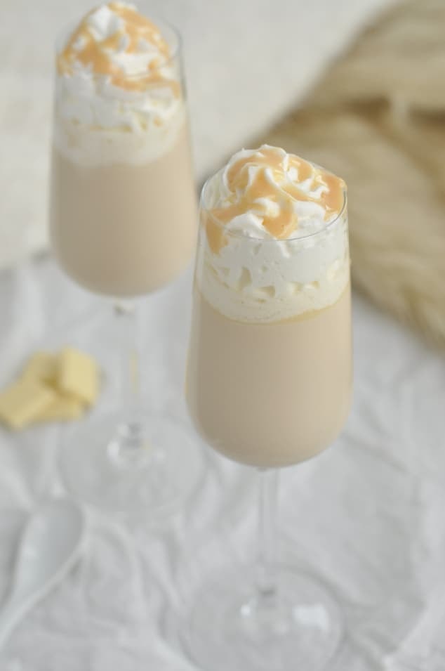 winter-snowflake-cocktail Two glasses of creamy cocktail topped with whipped cream and chocolate drizzle.