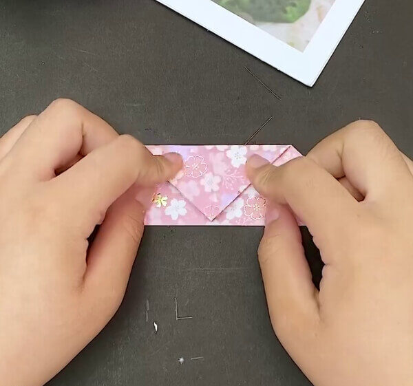 Making A Fold On The Top Corner Of The Triangle- Creating a heart-shaped envelope with the art of origami